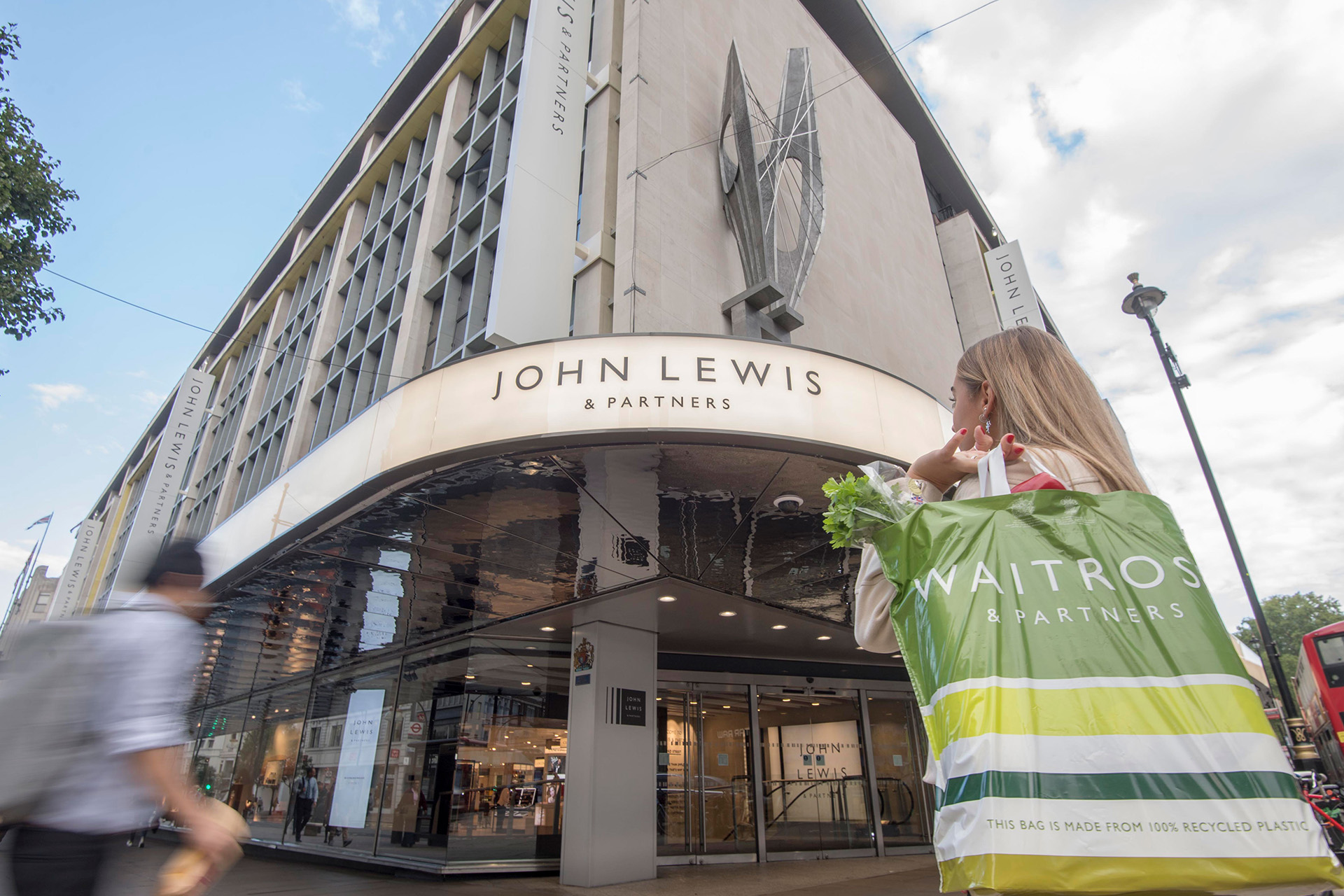 A customer leaving John Lewis & Partners on Oxford Street with a Waitrose bag